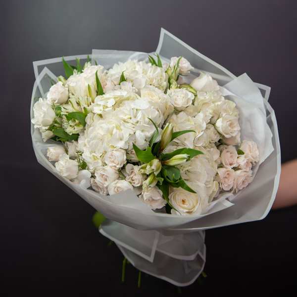 Bouquet of white roses and hydrangeas wrapped in pale paper
