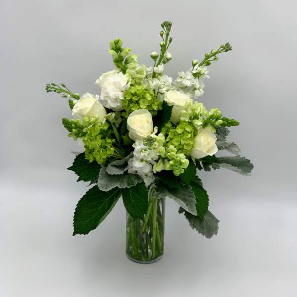 White roses and green blooms in a clear glass vase