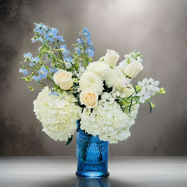 White and blue floral arrangement in a blue glass vase