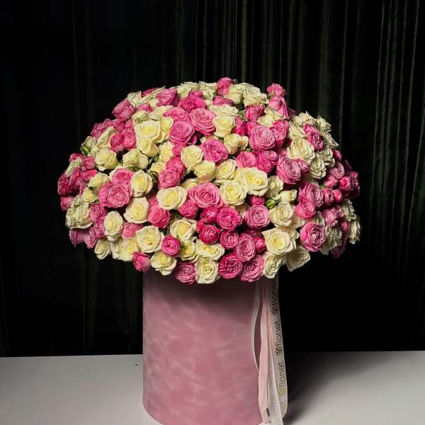 Large bouquet of pink and cream roses in a pink hat box
