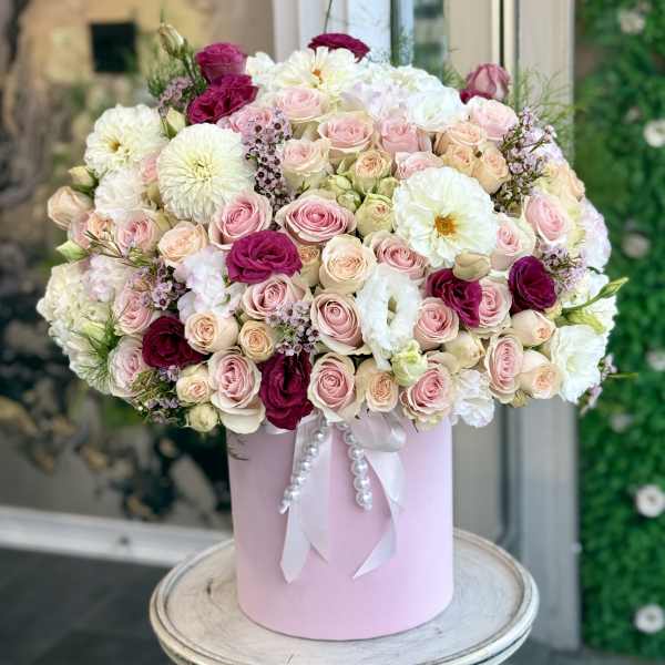 Large bouquet of pink, white, and burgundy roses in a pink hat box