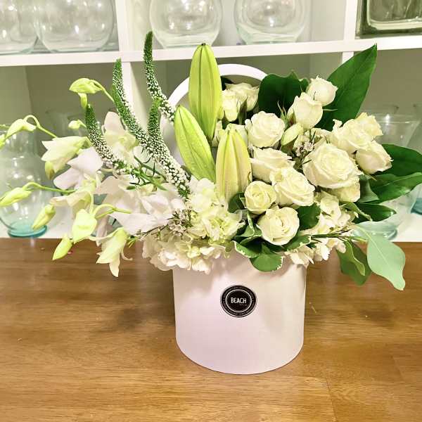 White roses and lilies arranged in a white hatbox