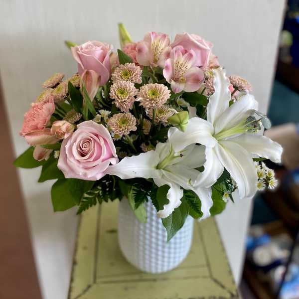 Pink roses and white lilies in a white vase