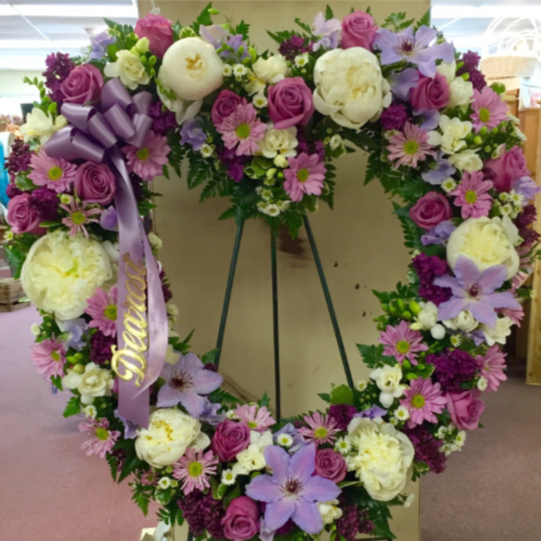 Heart-shaped floral wreath with pink, white, and lavender flowers on an easel