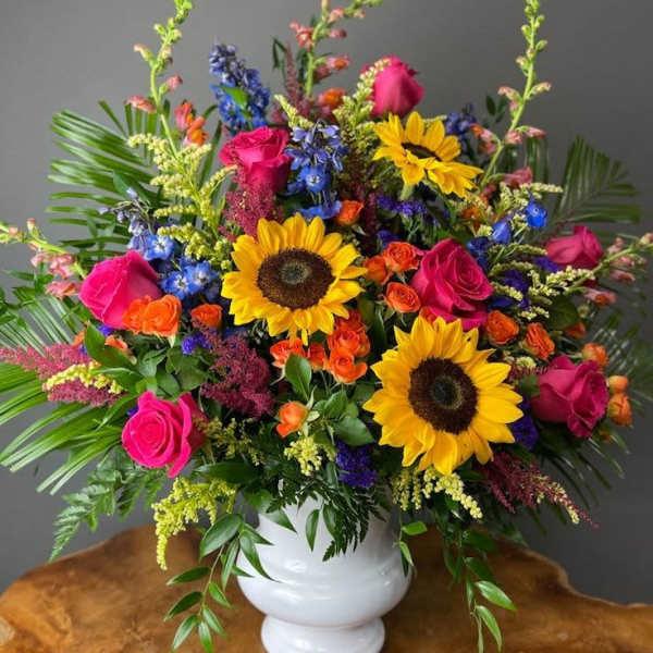 Bright mixed bouquet with sunflowers and pink roses in a white vase