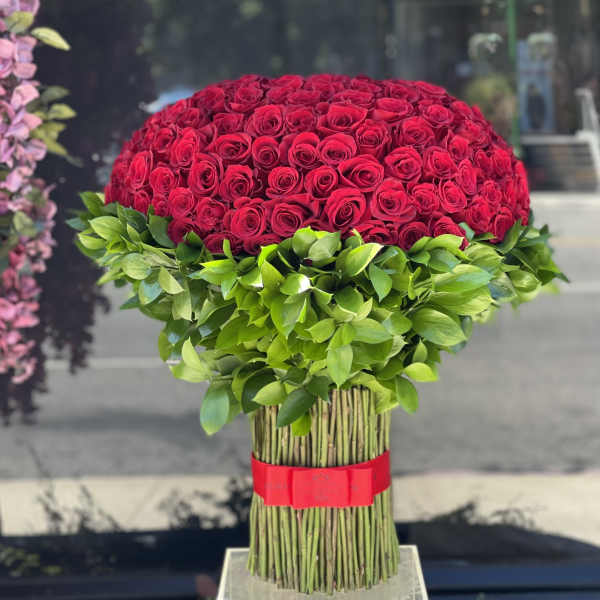 Large dome of red roses with green leaves and a red ribbon wrap