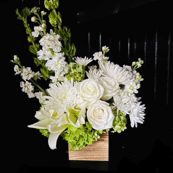 White floral arrangement in a wooden box with tall green spikes