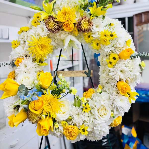 Yellow and white floral wreath on a stand