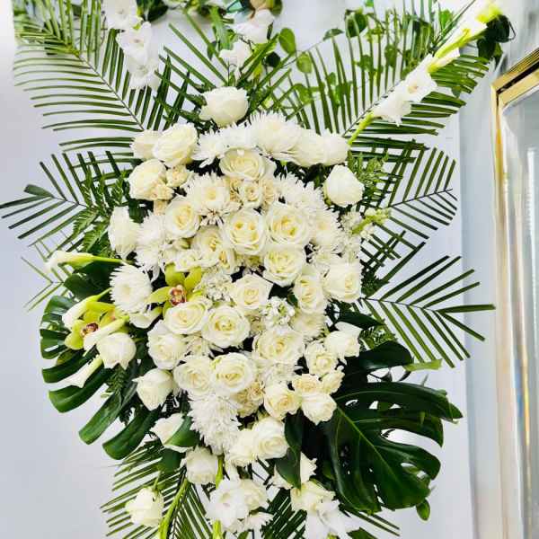 Large white floral standing spray with roses and lilies on a stand
