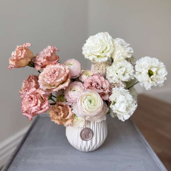 Pink and white flowers arranged in a white vase