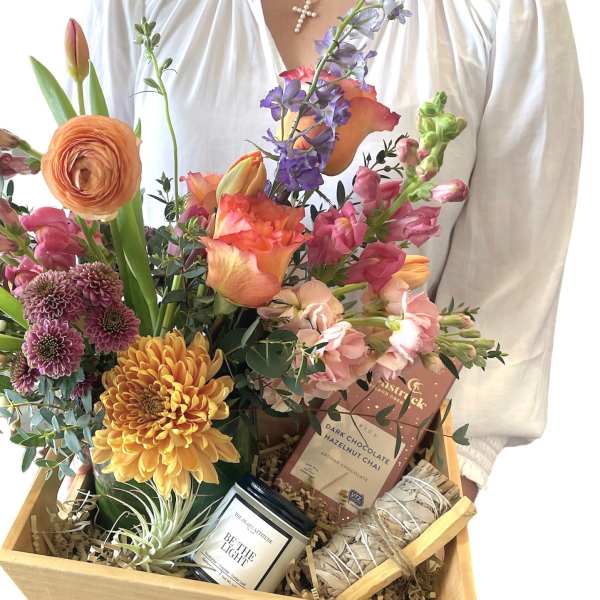 Mixed flower gift basket with candles and chocolate in a wooden crate