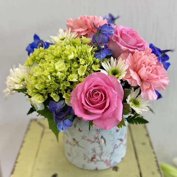 Pink roses, carnations, and daisies in a floral tin container