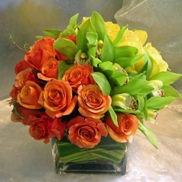 Bouquet of orange and yellow roses in a square glass vase