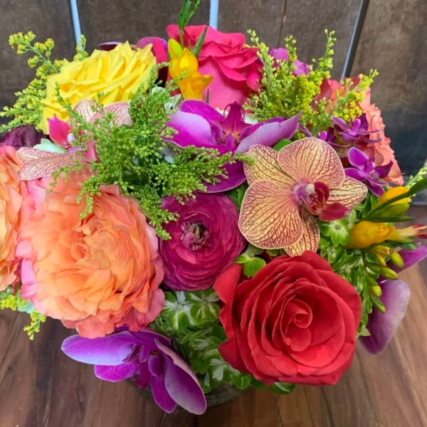 Colorful bouquet of roses, orchids, and ranunculus in a vase
