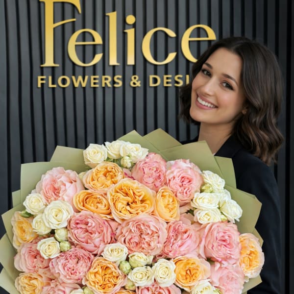Woman holding a large bouquet of pink, peach, and white roses