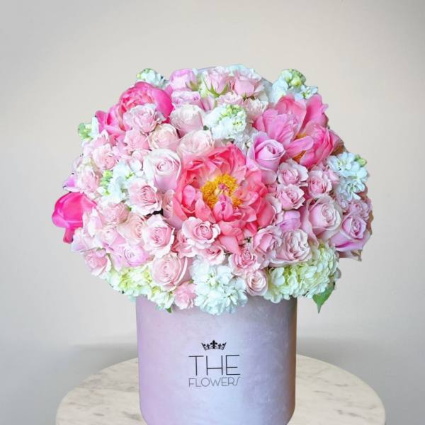 Pink and white flower arrangement in a lavender hat box
