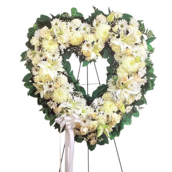 Heart-shaped white floral wreath on a stand with a ribbon