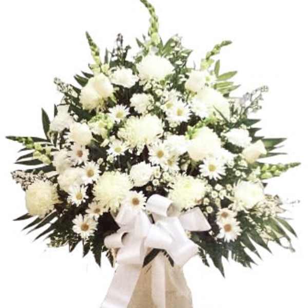 White floral standing spray with a ribbon on a pedestal