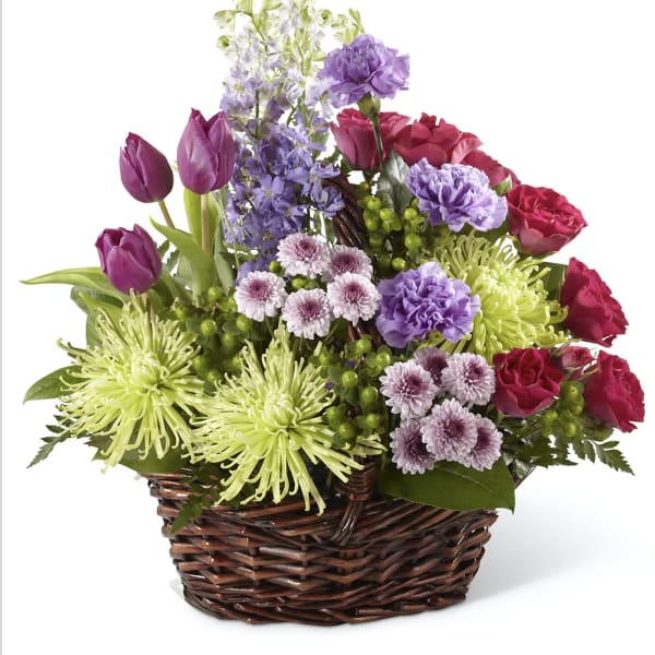 Mixed bouquet in a wicker basket with purple, pink, and green flowers