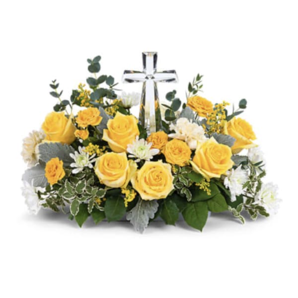 Yellow roses and white flowers arranged around a clear glass cross