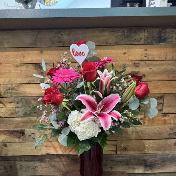 Bouquet of red roses, pink lilies, and white hydrangea in a vase