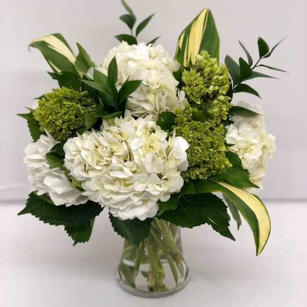 White hydrangea bouquet with green blooms in a clear glass vase