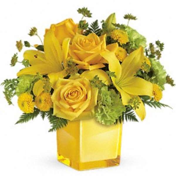Yellow roses and lilies arranged in a square glass vase
