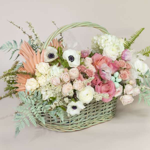 Pastel flower arrangement in a woven basket with pink and white blooms