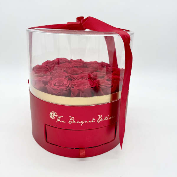 Red roses in a clear round gift box with a red ribbon