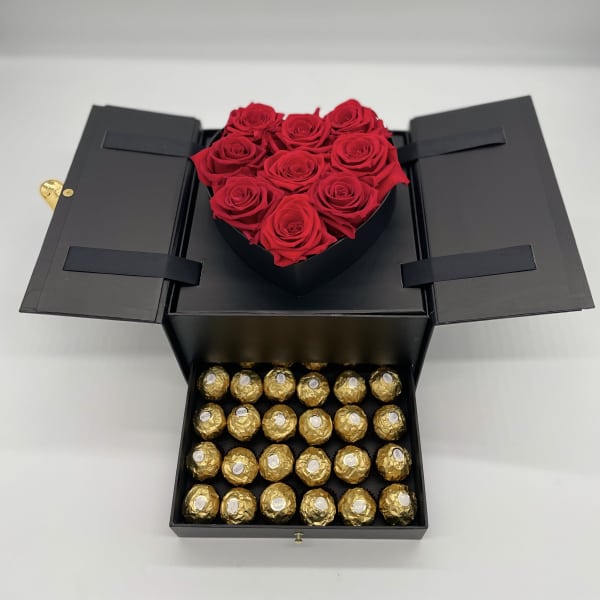 Black gift box with red roses on top and gold-wrapped chocolates below