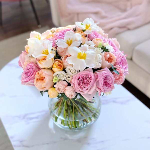 Pink and peach rose bouquet with white flowers in a glass vase