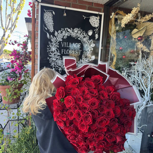 Large bouquet of red roses wrapped in burgundy paper