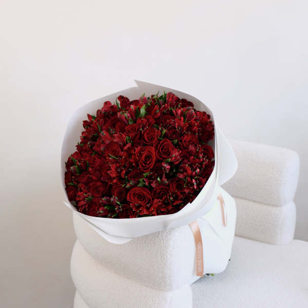 Bouquet of red roses and red alstroemeria wrapped in white paper