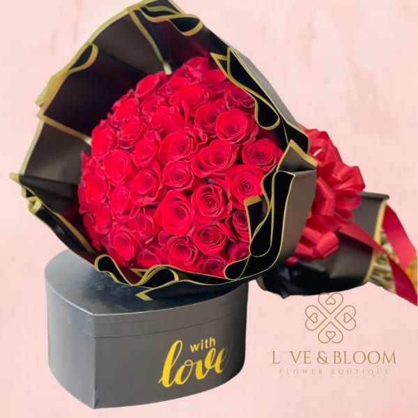 Bouquet of red roses in black and gold wrapping with a gift box