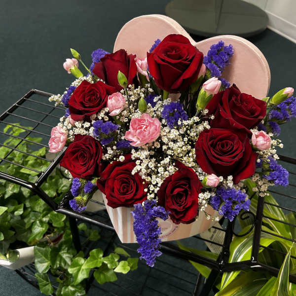 Heart-shaped box of red roses with pink carnations and purple filler flowers