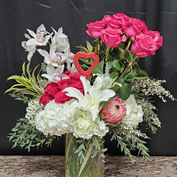 Bouquet of pink roses, white lilies, and orchids in a glass vase