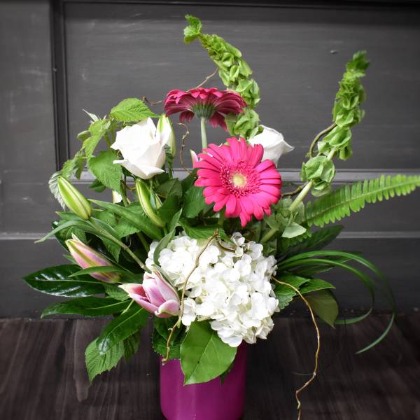 Pink gerbera daisies and white roses in a magenta vase