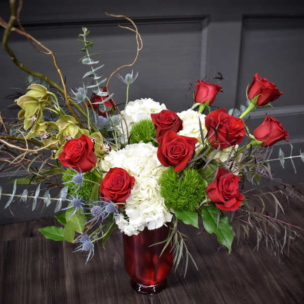 Red roses and white hydrangeas in a red vase with curly branches