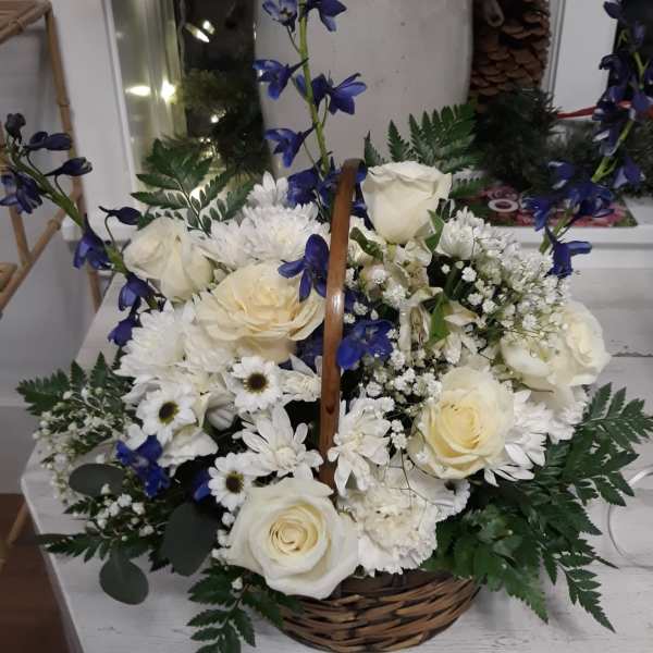 Basket arrangement of white roses and daisies with blue delphinium accents and ferns