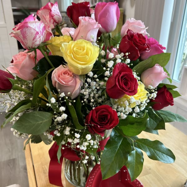 Bouquet of red, pink, and yellow roses in a glass vase