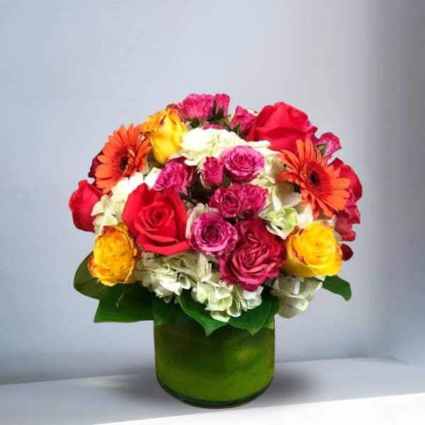 Mixed bouquet of roses, gerbera daisies, and hydrangeas in a green vase