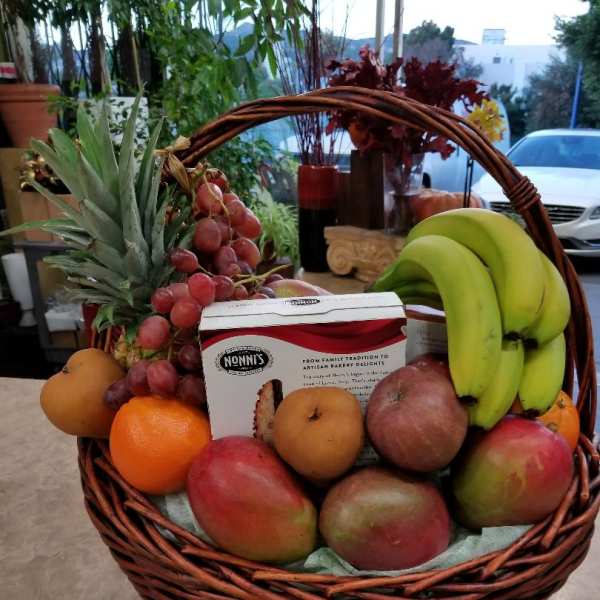 Fruit basket with bananas, grapes, mangoes, oranges, and a bakery box