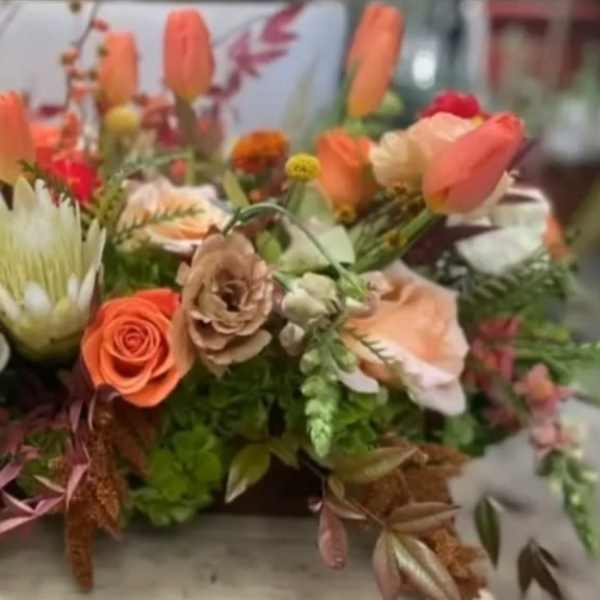 Low floral arrangement with peach, coral, white, and yellow blooms