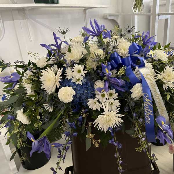 Large blue and white floral spray with ribbon in a container