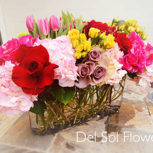 Mixed bouquet of roses, hydrangeas, and tulips in a glass vase