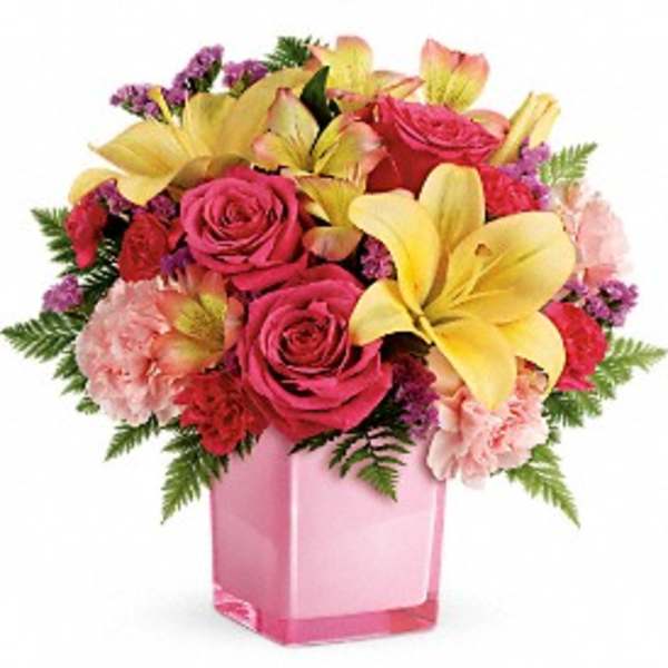 Pink roses and yellow lilies arranged in a pink glass vase