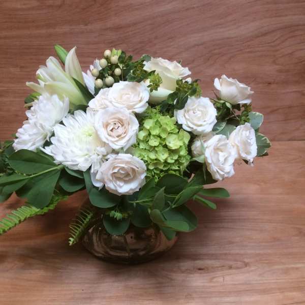 White roses and chrysanthemums arranged in a low glass vase
