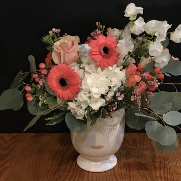Bouquet of pink gerberas, white hydrangeas, and roses in a face vase
