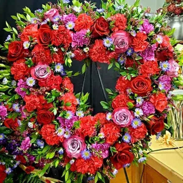 Heart-shaped floral wreath with red and pink roses and small purple flowers