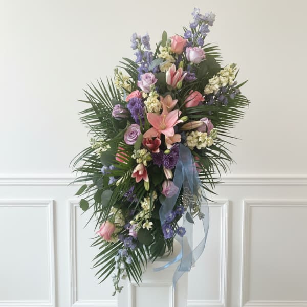 Tall floral spray with pink and lavender blooms on a white pedestal